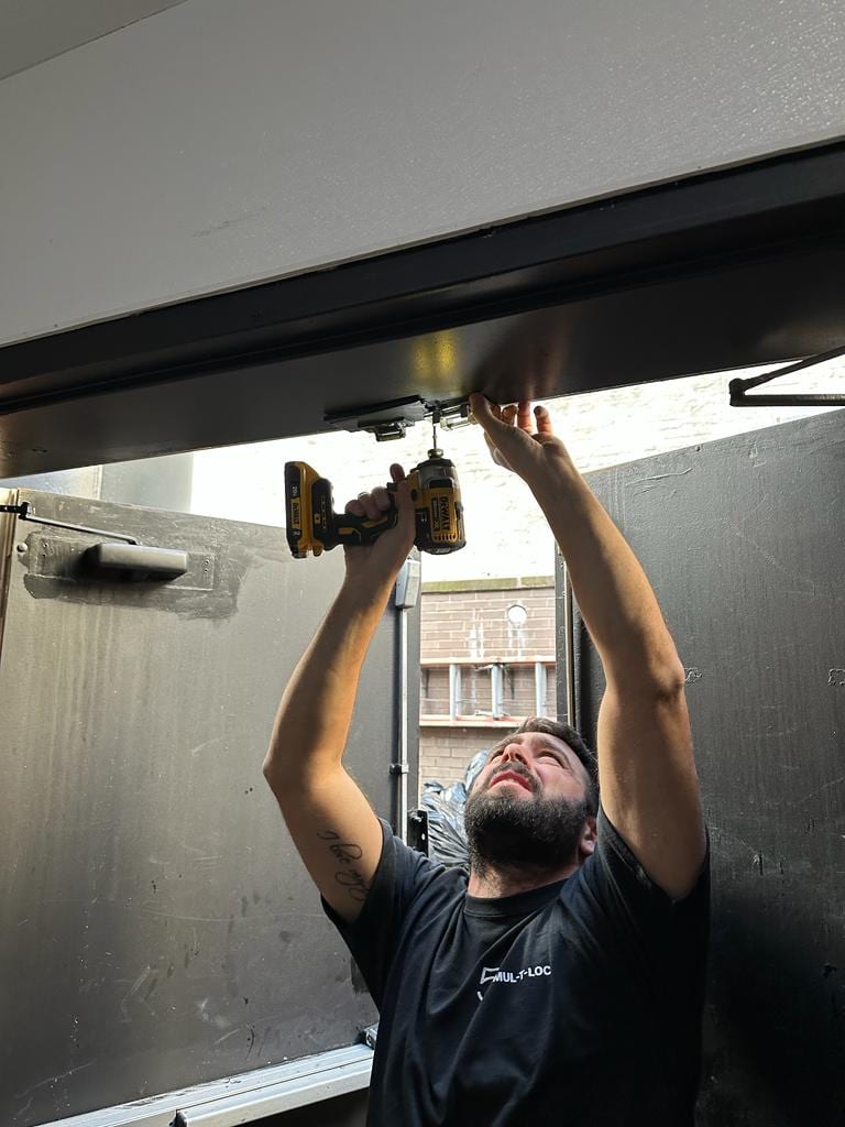 Sunny Locksmith technician installing a commercial panic bar on a metal door